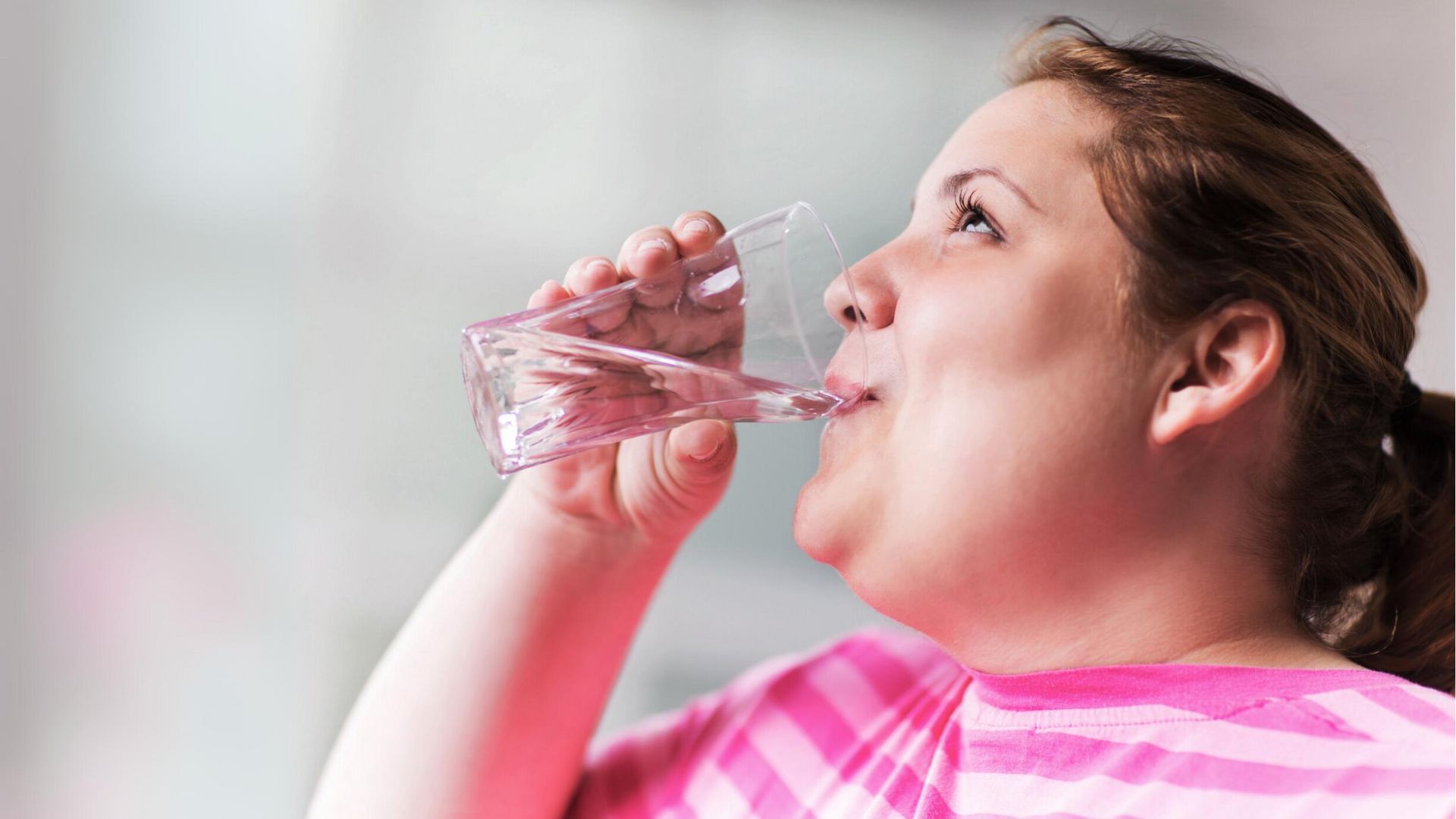 Woman drinking water from a clear glass cup