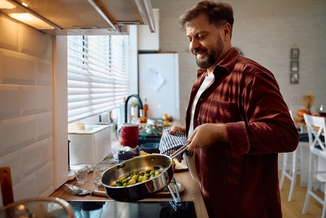 Man in red check cooking kitchen veg warm low light