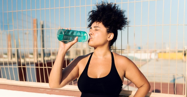 Women sipping water from a sports bottle during a training session outside