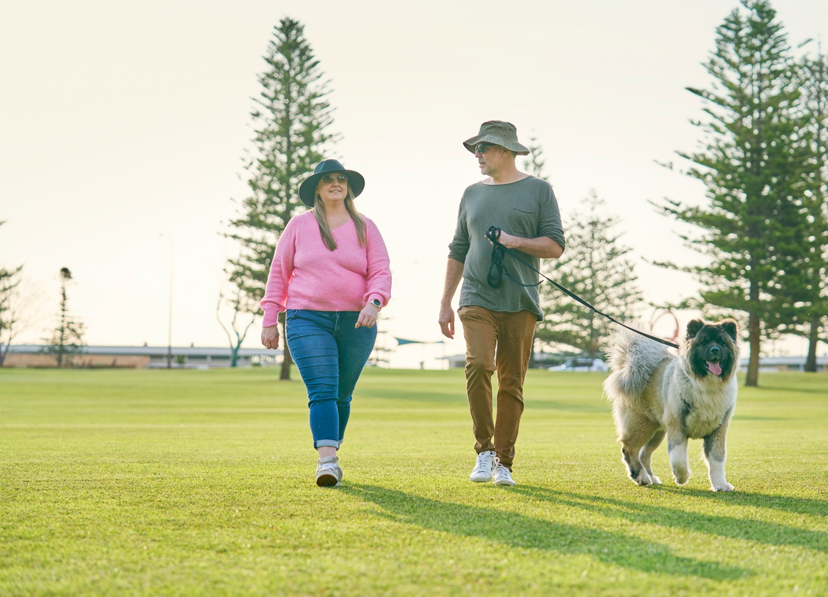 Two people walking their dog in a park